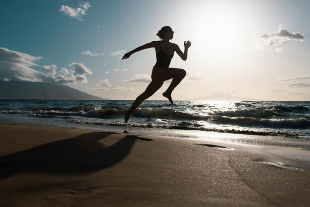 Silhouet van een hardlopervrouw die traint in het hardlopen van een sprinttraining op het strand, gezond joggen in de buitenlucht