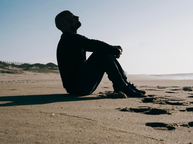 Silhouet van een jonge man die diep frisse lucht inademt op het strand met kopieerruimte