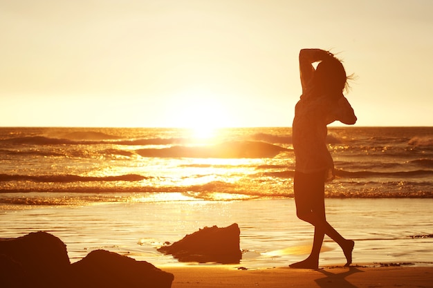 Silhouet van een jonge vrouw die zich op strand bevindt