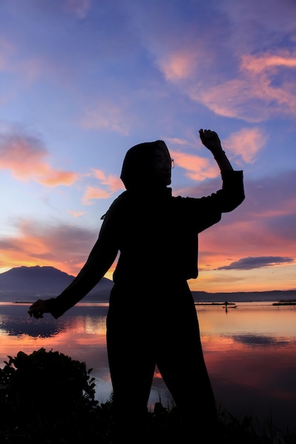 Silhouet van een jonge vrouw die zich voordeed tegen een prachtige zonsondergang op de achtergrond