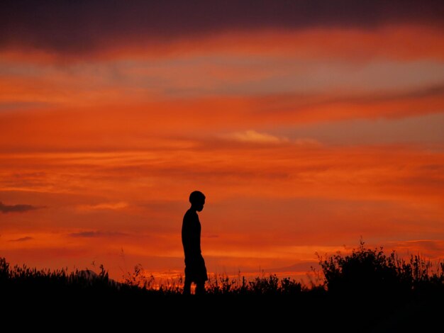Silhouet van een jongen tegen een bewolkte hemel in de schemering
