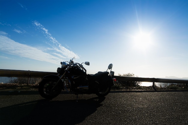 Silhouet van een klassieke motorfiets onder een felle zon