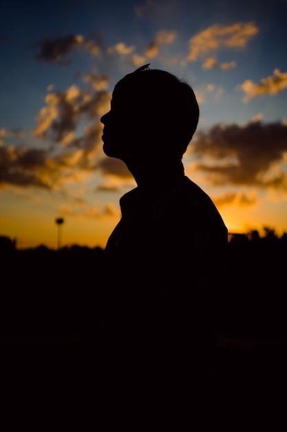 Silhouet van een knappe jonge man bij zonsondergang.