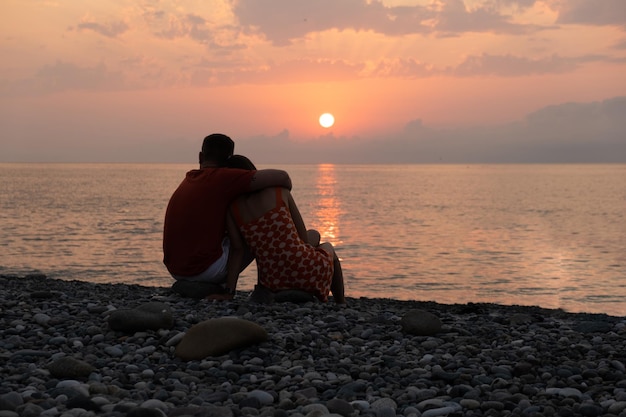 Silhouet van een knuffelend paar aan de kust in de beschermende zon.