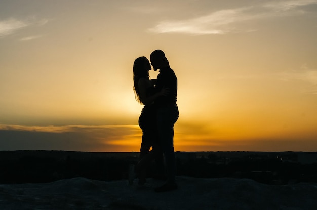 silhouet van een liefdevol paar omarmen bij zonsondergang