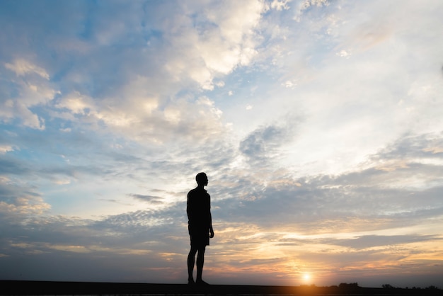 Silhouet van een man gelukkig bij zonsondergang.