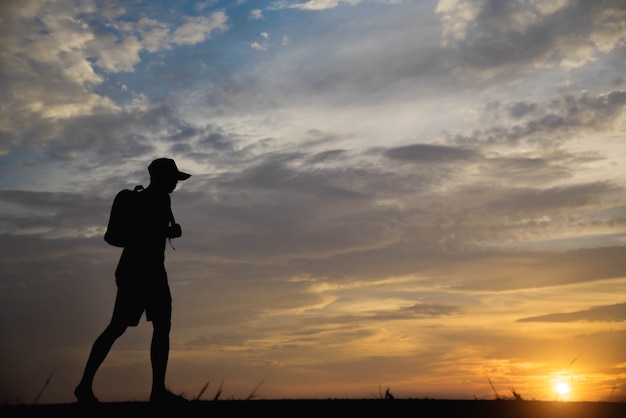 Silhouet van een man gelukkig wandelen bij zonsondergang.