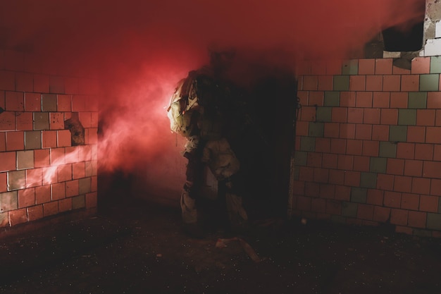 silhouet van een man in uniform met een wapen in een oude gang in rode rook