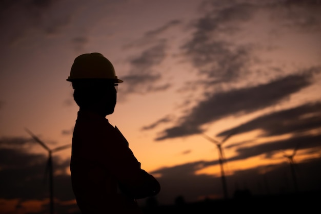 Silhouet van een man-ingenieur die werkt en het rapport vasthoudt bij het Power Generator Station van het windturbinepark op mensen in bergThailand