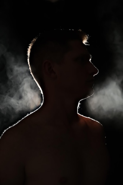 Silhouet van een man mannen in de donkere rook stoom man in een donkere kamer