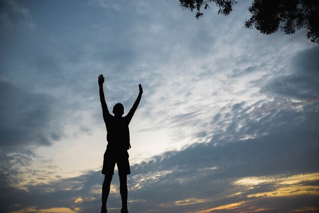 Silhouet van een man springen met gelukkig in de zonsondergang.