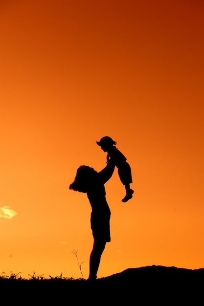 silhouet van een moeder en zoon buiten spelen bij zonsondergang