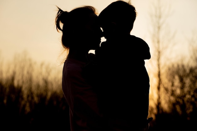 Foto silhouet van een moeder en zoon die buiten spelen bij zonsondergang moederdag concept