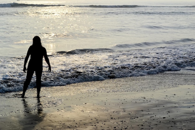 silhouet van een persoon aan de kust bij zonsondergang gouden uur