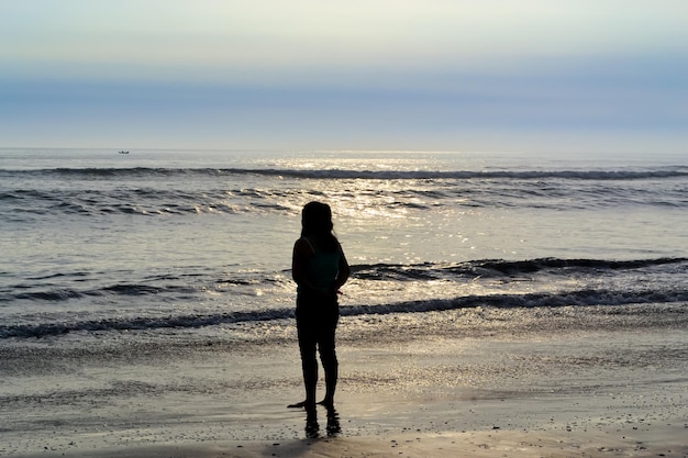 silhouet van een persoon aan de kust bij zonsondergang gouden uur