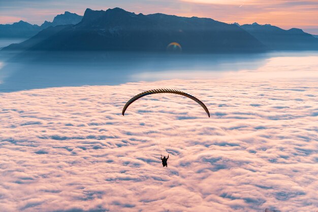 Foto silhouet van een persoon die met een paraglider over een wolkenlandschap vliegt