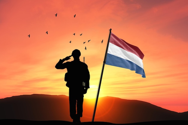 Foto silhouet van een soldaat met de nederlandse vlag tegen zonsondergang of zonsopgang