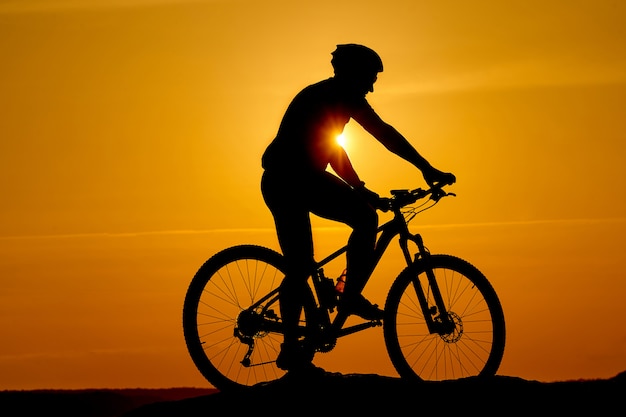 Silhouet van een sportieve fietser in helm op een fiets