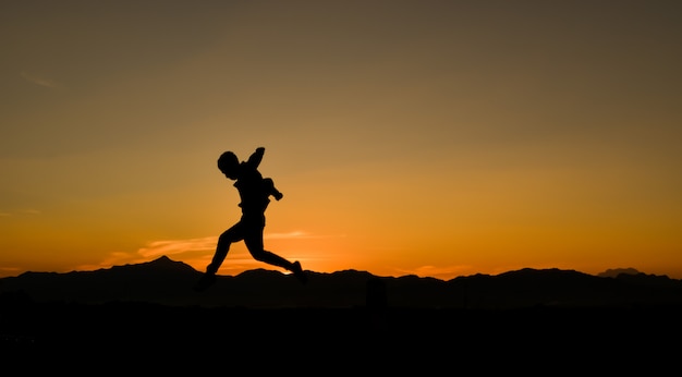 Silhouet van een springende man bij zonsondergang