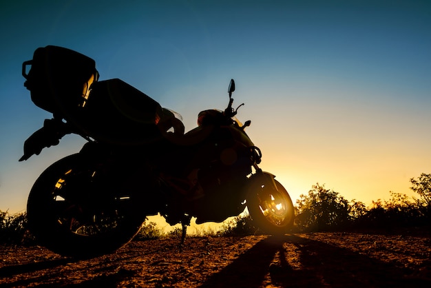 Silhouet van een touring motor geparkeerd bij zonsondergang