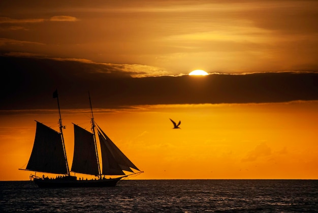 Silhouet van een tweemast zeilboot bij zonsondergang