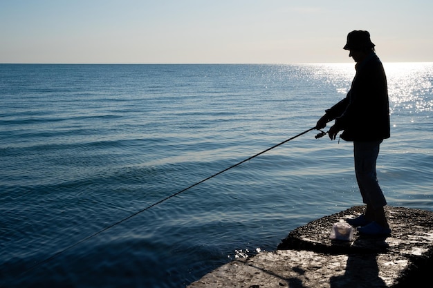 Silhouet van een visser vangt vis op zee