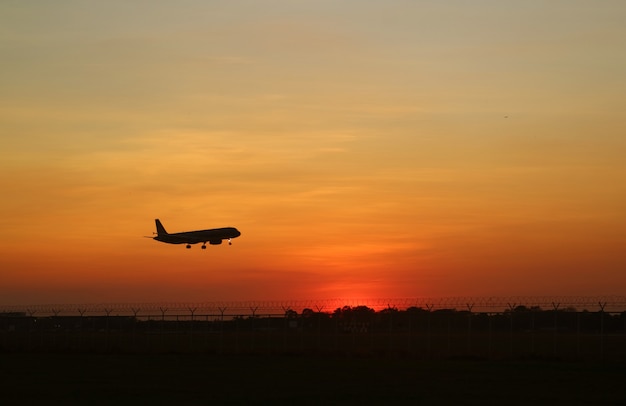 Silhouet van een vliegtuig dat opstijgt tot aan de zonsopganghemel