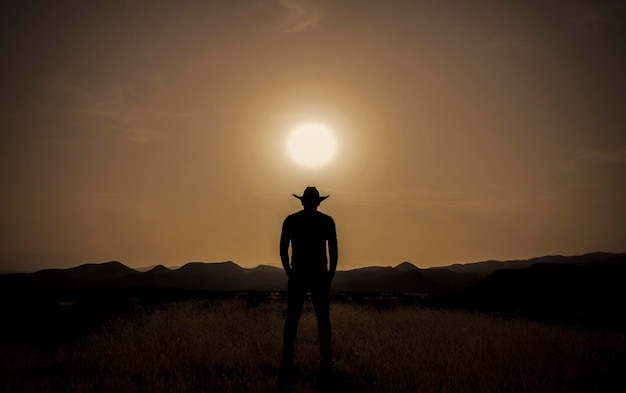 Foto silhouet van een volwassen man die tijdens de zonsondergang in de woestijn staat.