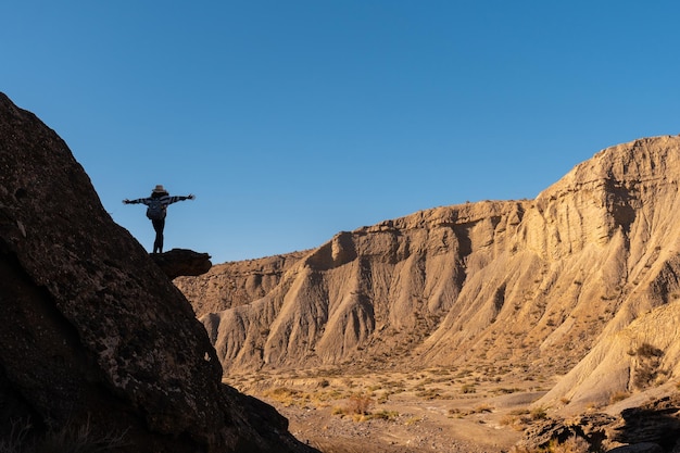 Silhouet van een vrije jonge vrouw met open armen die een rots beklimt in de woestijn van Tabernas, provincie AlmerÃÃ‚Âa, Andalusië. Een trektocht in de Rambla Las Salinas