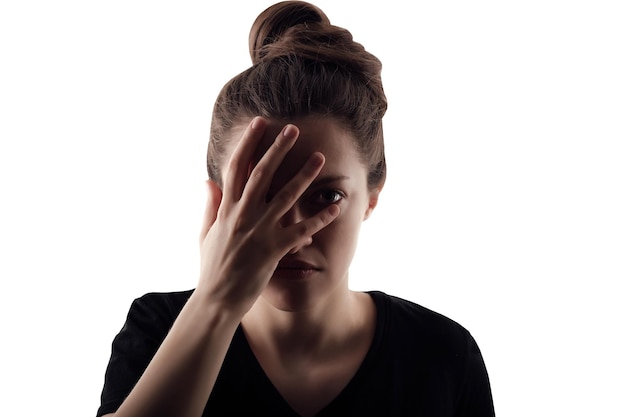 Silhouet van een vrouw die het halve gezicht met de hand sloot, geïsoleerd portret op een witte achtergrond