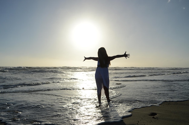 Silhouet van een vrouw die op het strand staat