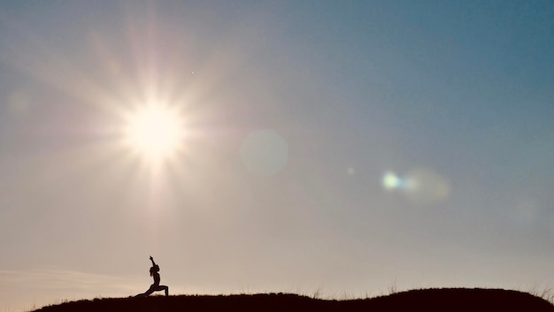 Silhouet van een vrouw die yoga fitness in de natuur doet op een zonnige dag Man met zijn rug in een Anjaneyasana pose gezond vrouwelijk lichaam in sportkleding bij zonsondergang