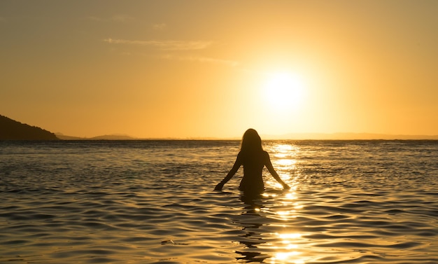 Silhouet van een vrouw in de zee bij zonsondergang