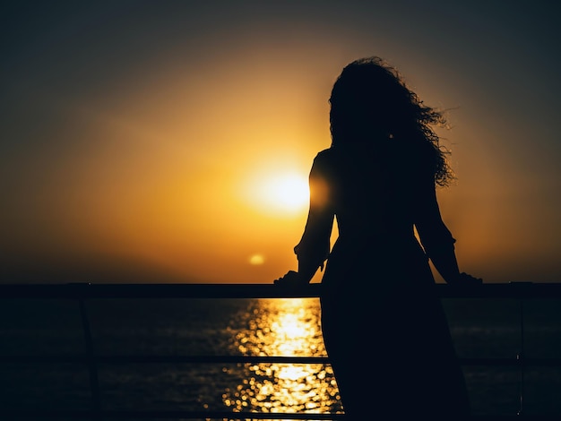 Silhouet van een vrouw op het strand bij zonsondergang