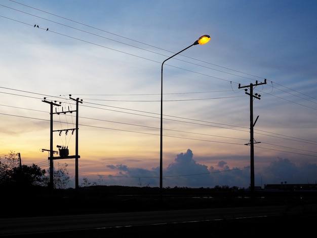 Silhouet van elektrische polen en kabels over de achtergrond van de zonsopganghemel. Energie en technologie.