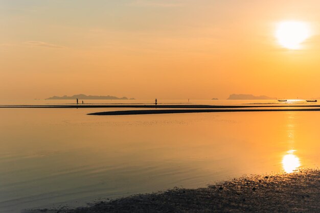 Silhouet van familie spelen op het strand bij zonsondergang