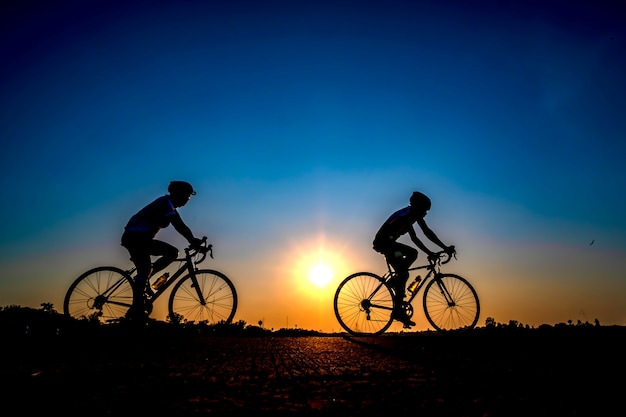 Silhouet van fietser op zonsondergangachtergrond.