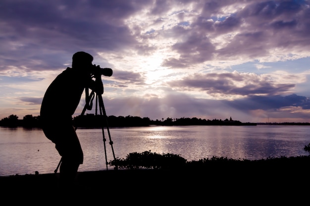 silhouet van fotograaf die foto neemt bij zonsondergang