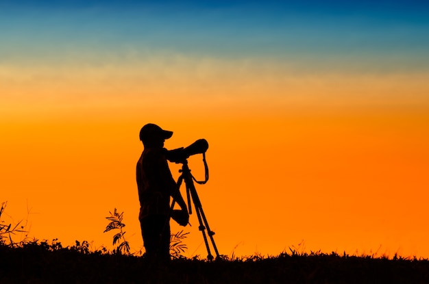 silhouet van fotograaf die foto van landschap tijdens zonsondergang