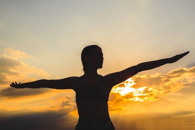 Silhouet van jonge vrouw het beoefenen van yoga bij zonsondergang