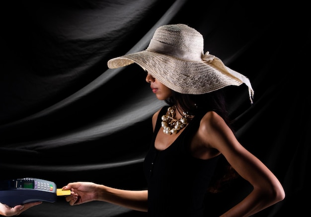 Silhouet van jonge vrouw met gouden creditcard kopen op online apparaat over gordijngordijn zwart