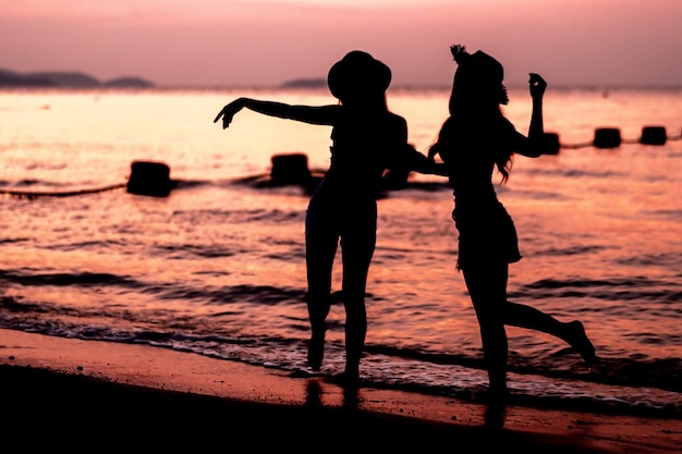 Silhouet van jonge vrouw twee die pret op het overzeese strand heeft