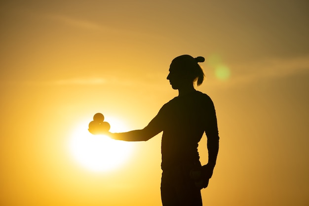 Silhouet van jongleur met ballen op kleurrijke zonsondergang.