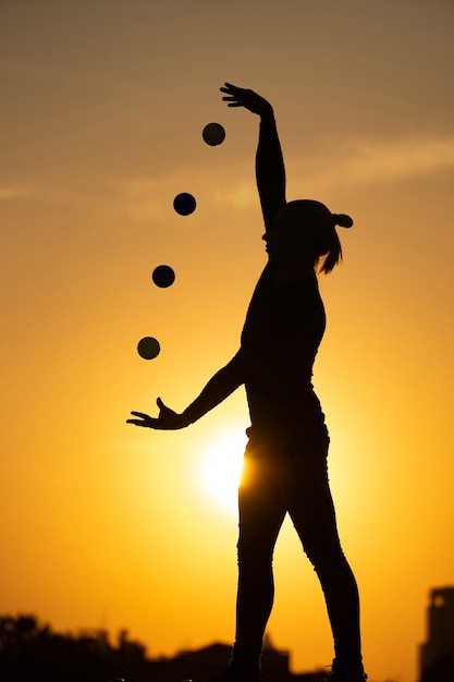 Foto silhouet van jongleur met ballen op kleurrijke zonsondergang.