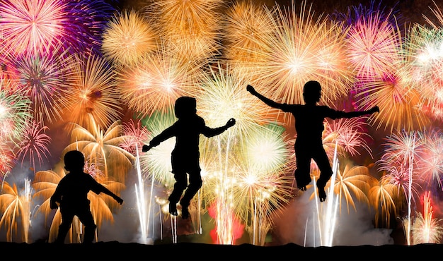 Silhouet van kinderen die over kleurrijk vuurwerk springen