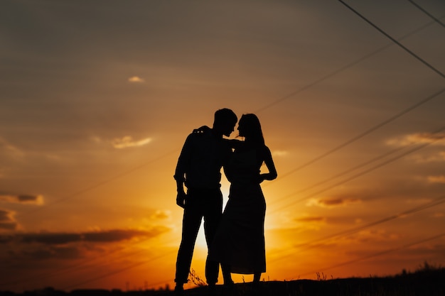 Silhouet van liefdevol paar staande rivier. Koppel tegen de prachtige zonsonderganghemel.