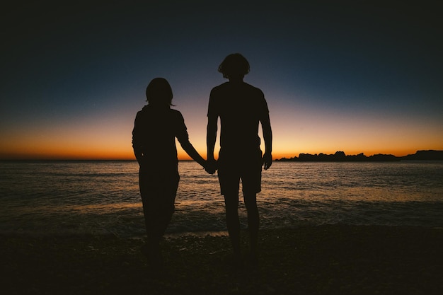 Silhouet van liefdevolle paar op oranje zonsondergang achtergrond