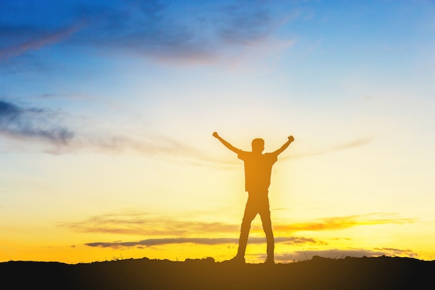 Silhouet van Man Viering Succes Geluk op een bergtop Avondhemel Zonsondergang Achtergrond.