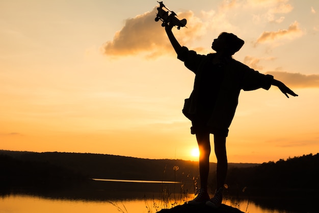 Silhouet van meisje die houten vliegtuig in aard spelen