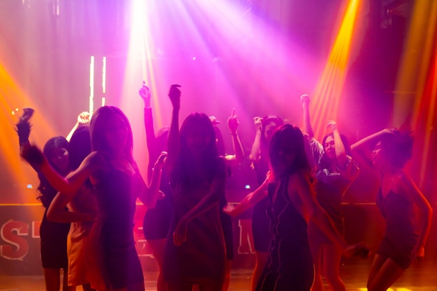 Silhouet van mensen dansen in disco nachtclub op muziek van Dj op het podium